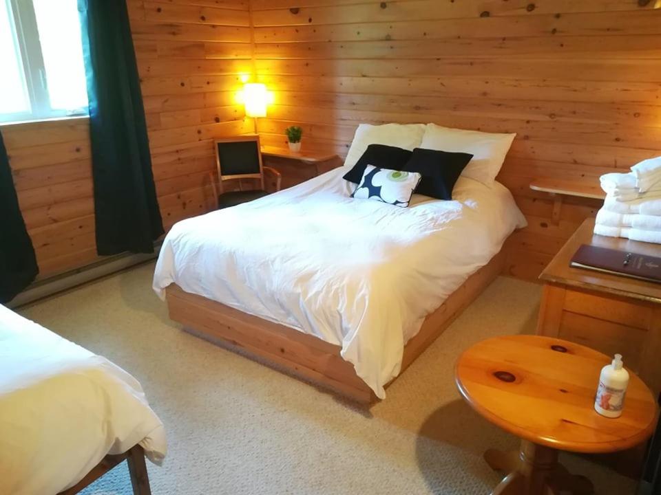 1 dormitorio con 1 cama en una cabaña de madera en Auberge Ma Maison, en Sainte-Melanie