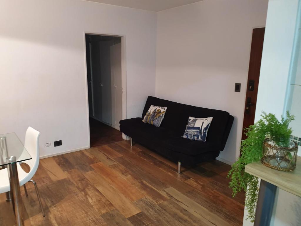 a living room with a black couch and wooden floors at Apartamento in Rosario