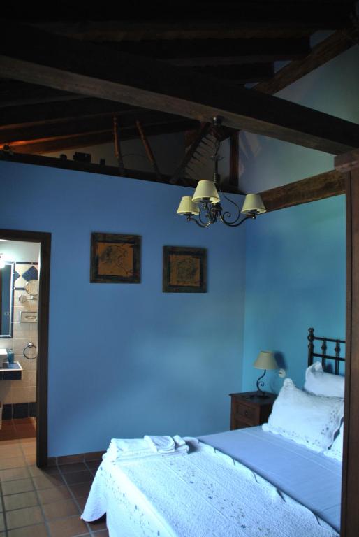 1 dormitorio con una pared azul y 1 cama en Casa Rural Los Regajales en Tenzuela