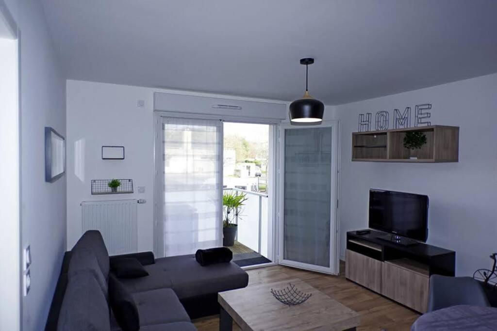 a living room with a couch and a tv at T2 moderne, lumineux, proche de la mer et des principaux accès routiers in Saint-Nazaire