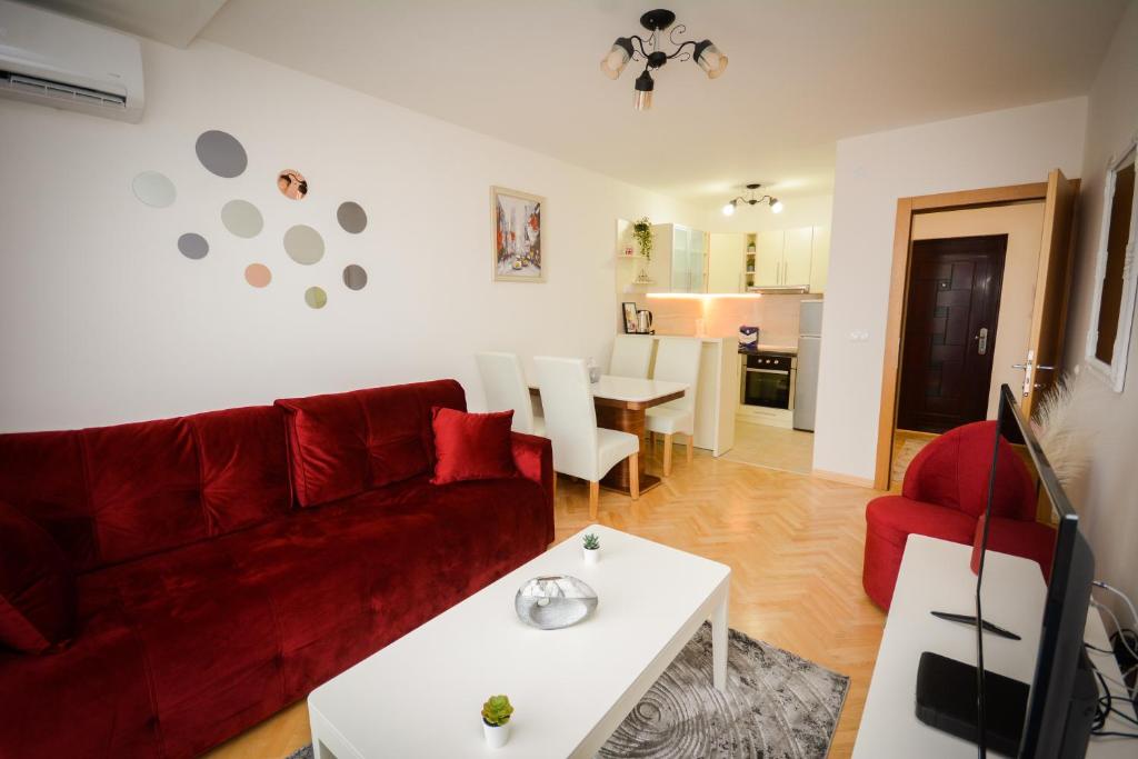 a living room with a red couch and a table at Apartman NINA in Vrnjačka Banja