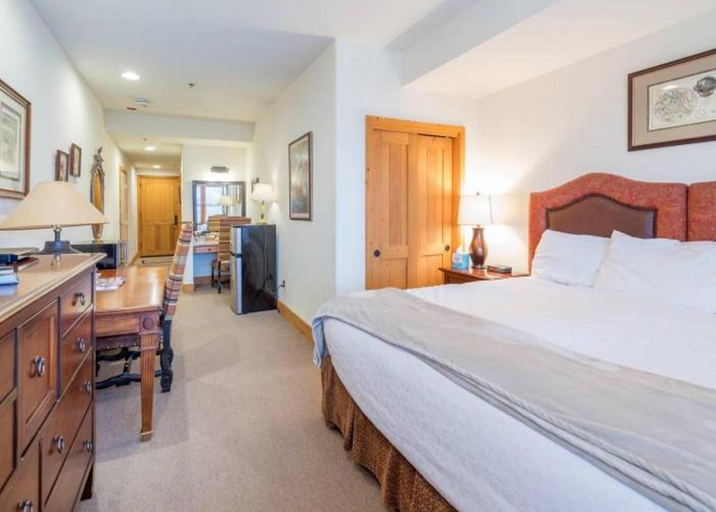 a bedroom with a large bed and a desk and a kitchen at Bear Creek Lodge in Telluride