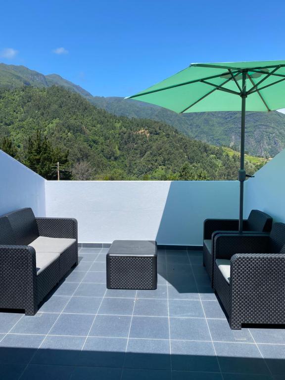 un patio con 2 sillas y una sombrilla verde en Sebastian's Apartment, en São Vicente