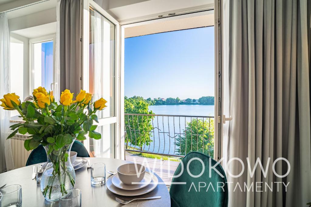 uma sala de jantar com uma mesa com um vaso de flores amarelas em WIDOKOWO Apartamenty em Ełk