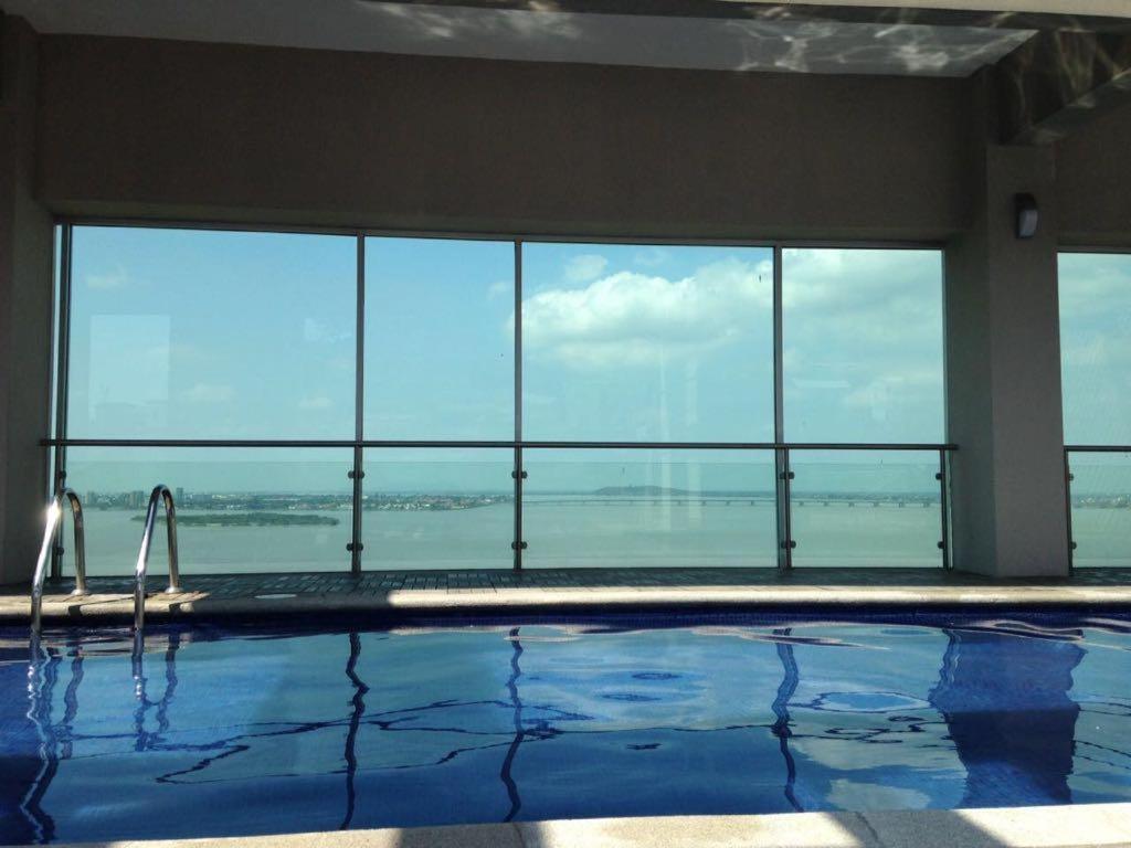 a large swimming pool with a view of the ocean at River View Suites Guayaquil in Guayaquil