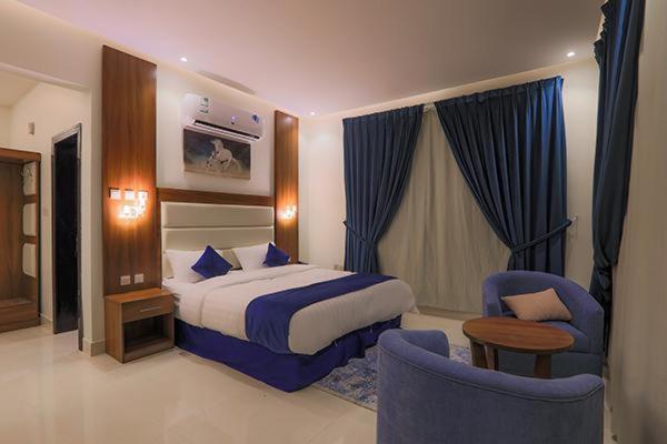 ein Hotelzimmer mit einem Bett und zwei Stühlen in der Unterkunft فرس ابها للاجنحة الفندقية in Abha