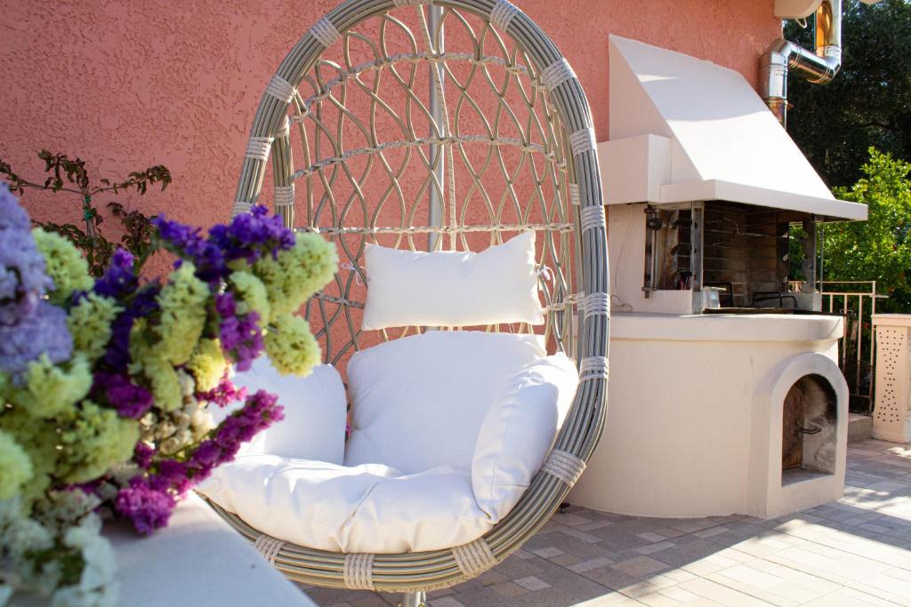 una sedia di vimini seduta su un patio fiorito di Cristina Apartments a Gaios