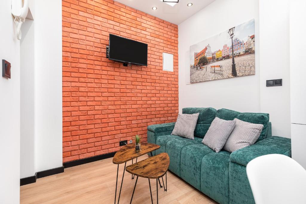 un soggiorno con divano verde e parete in mattoni di Bm apartamenty Wały Chrobrego Radogoska Parking a Stettino