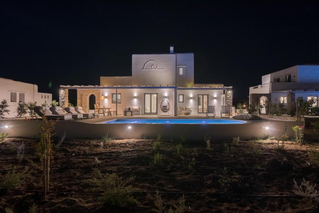 a villa with a swimming pool at night at Isalos Villas Naxos in Naxos Chora