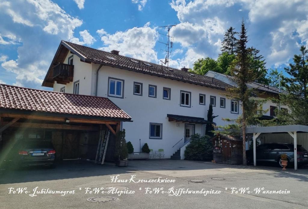 een groot wit huis met een garage ervoor bij Haus Kreuzeckwiese - Self Catering Apartments in Garmisch-Partenkirchen