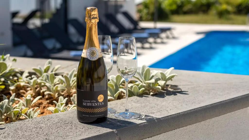 butelkę szampana i dwie szklanki na stole. w obiekcie Luxury Villa Subventus w Krku