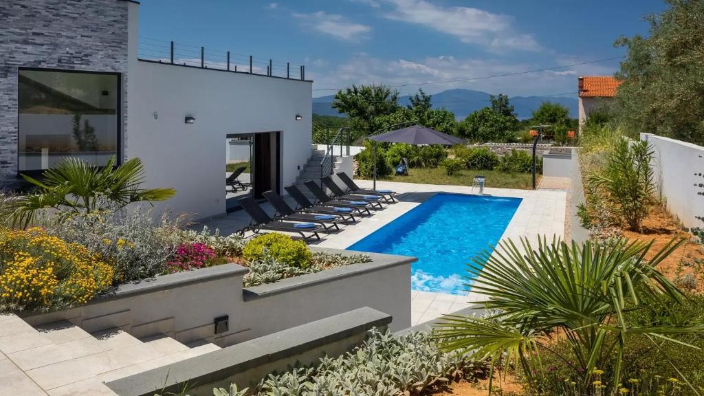 a backyard with a swimming pool with chairs and plants at Luxury Villa Subventus in Krk