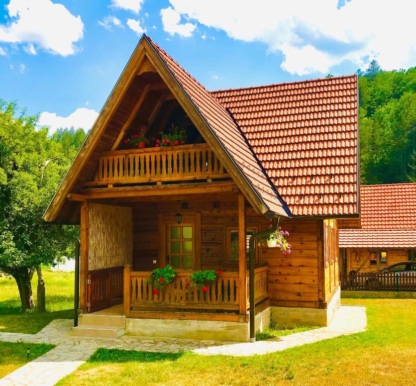 a log cabin with a porch and flowers on it at Apartmani d&s in Mokra Gora