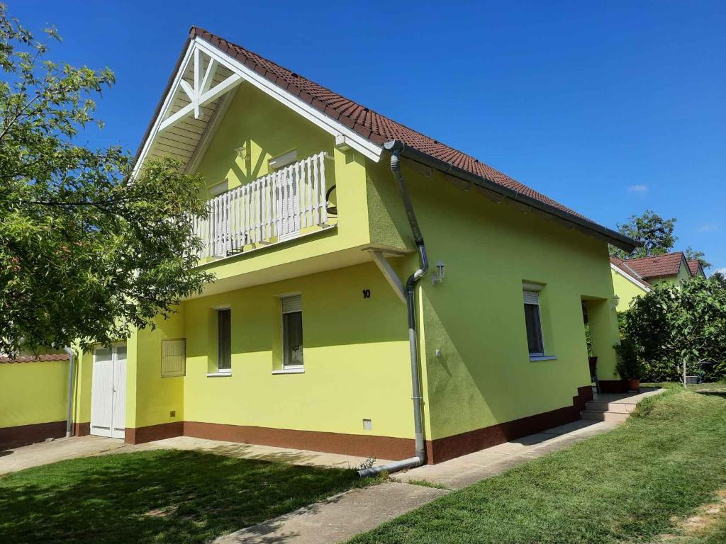 een geel en groen huis met een balkon bij Holiday home in Balatonbereny 34655 in Balatonberény