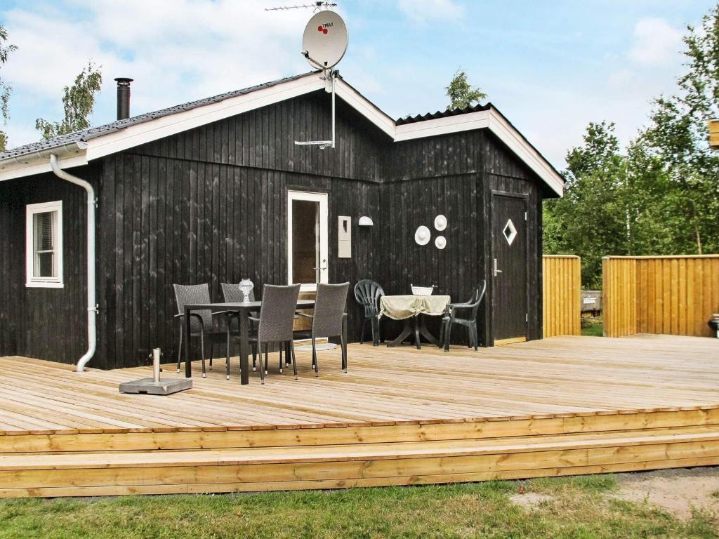 een zwarte schuur met een tafel en stoelen op een houten terras bij Holiday home Hals IX in Hals