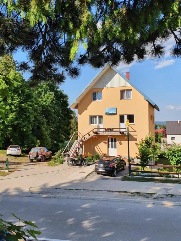 una casa grande con un coche aparcado en un aparcamiento en Apartments Lalović en Žabljak