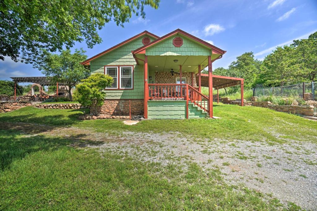 a small green house with a deck on a yard at Charming Hilltop Cottage in Medicine Park! in Medicine Park