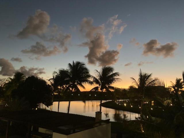 a sunset with palm trees and a body of water at Praia do Forte- Iberostar- Ap Luxuoso 3 qts in Mata de Sao Joao