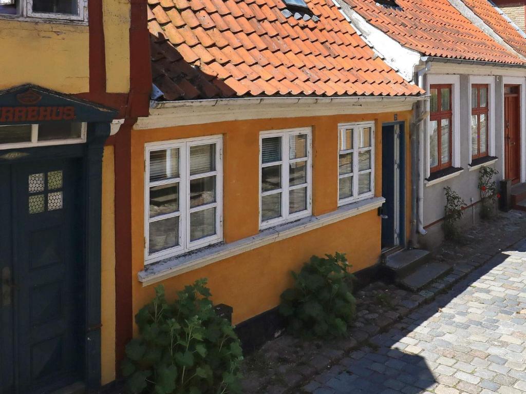 ein orangefarbenes Haus mit weißen Fenstern und einer Straße in der Unterkunft 3 person holiday home in r sk bing in Ærøskøbing