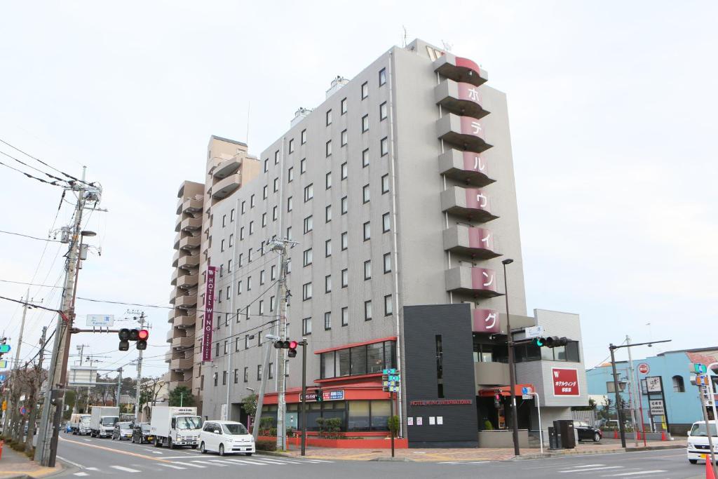 un edificio blanco alto en una calle de la ciudad con tráfico en Hotel Wing International Sagamihara, en Sagamihara