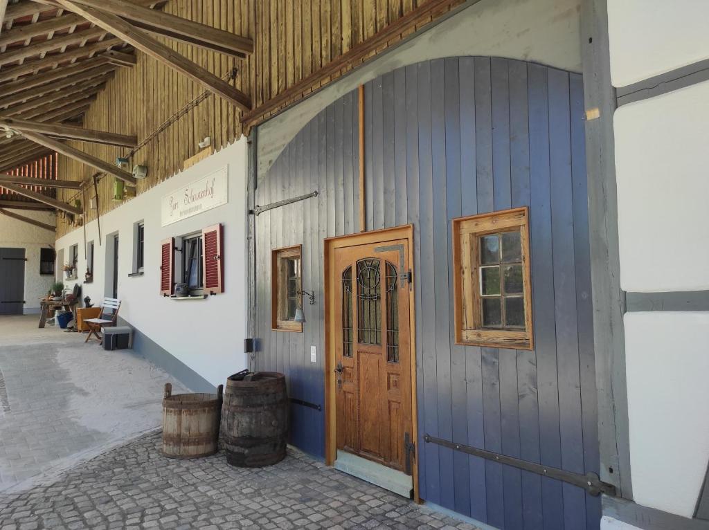 a barn with a wooden door and some barrels at Zum Scheunenhof - Scheune in Ichenhausen