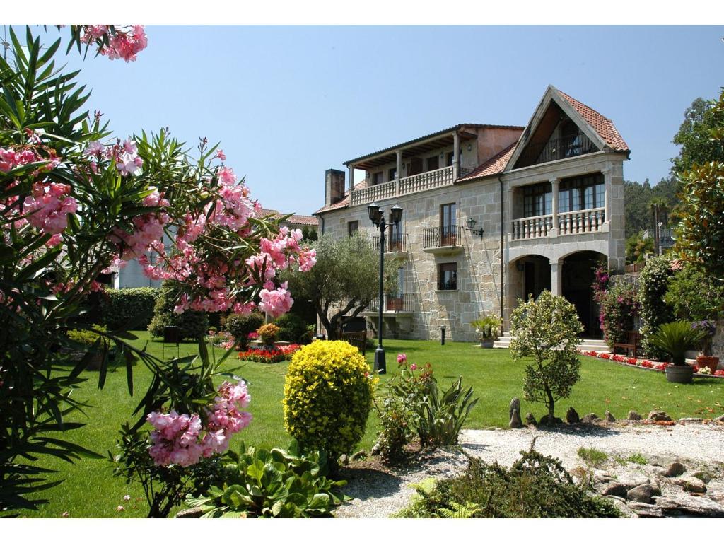 una vecchia casa in pietra con fiori rosa nel cortile di Casa Antiga Do Monte a Lestrove