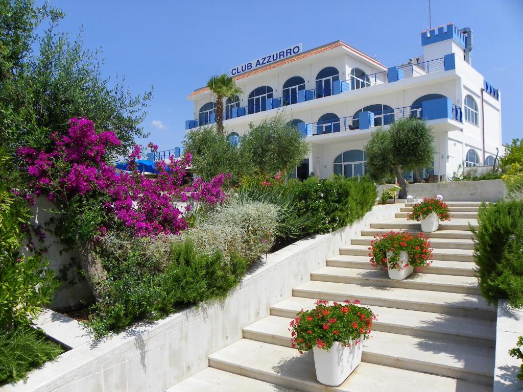 um edifício com escadas e flores em frente em Club Azzurro Hotel & Resort em Porto Cesareo