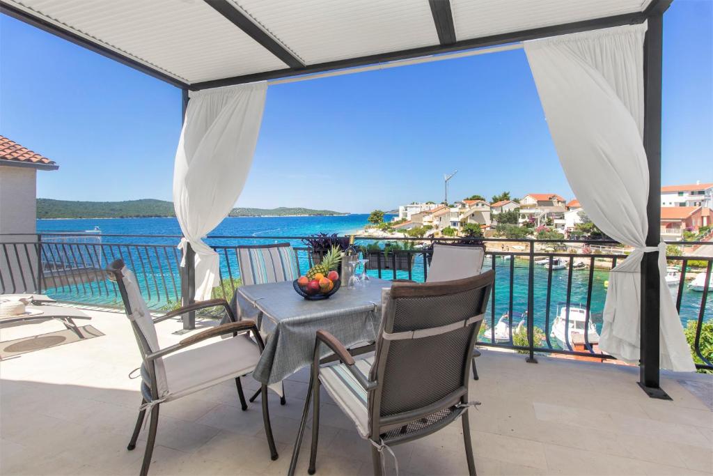 einen Tisch und Stühle auf einem Balkon mit Blick auf das Wasser in der Unterkunft Villa Vala in Zaboric