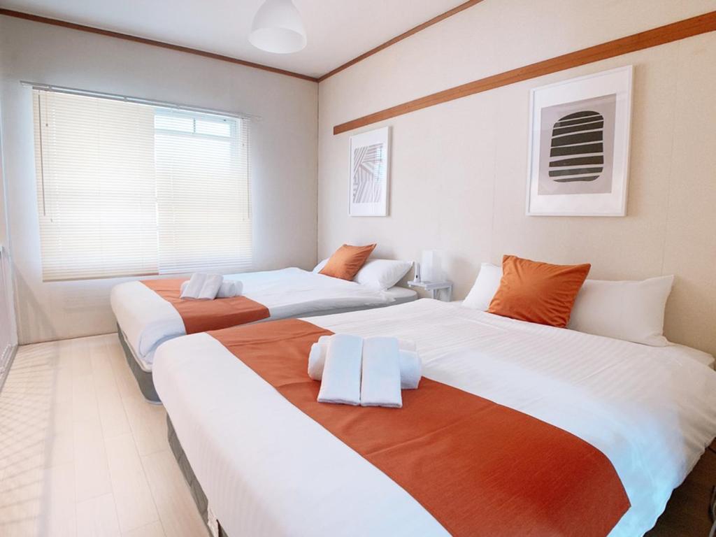 two beds in a room with white and orange at OUCHI HOTEL Kanayama-cho with Dogs in Hiroshima
