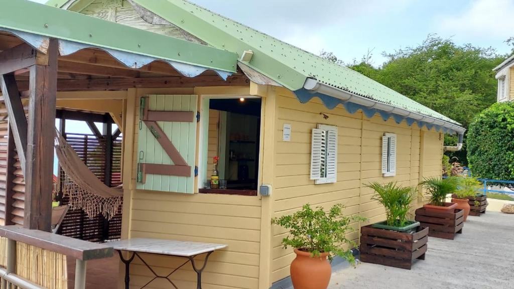 une petite maison jaune avec un auvent vert dans l'établissement La cabane du pêcheur, au Gosier
