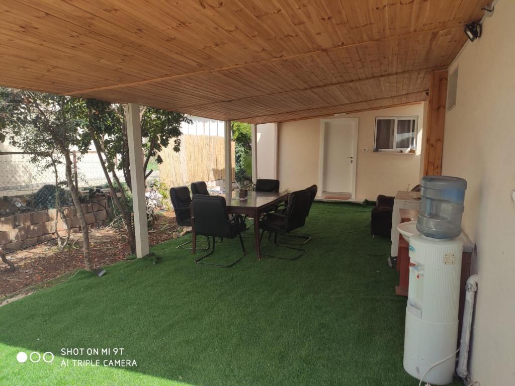 eine Terrasse mit einem Tisch und Stühlen auf Gras in der Unterkunft גני התניא in Safed