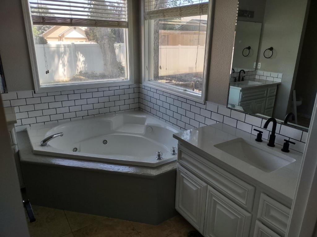 a bathroom with a tub and two sinks and a mirror at Meridian BnB ID - Pristine 4BR 2BA Spacious Home In The Heart Of Meridian Near Boise in Meridian