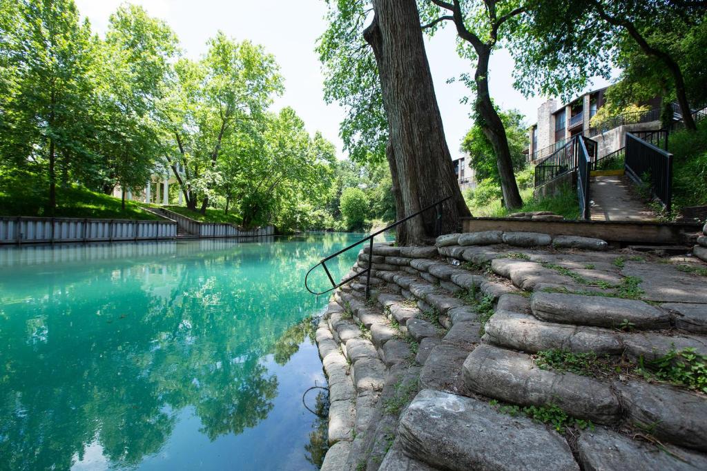 a stone wall next to a river with trees at The Float Inn 3 CW B209 in New Braunfels