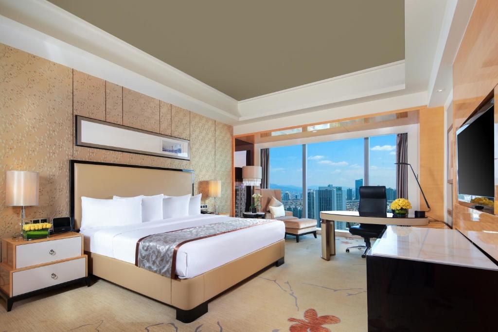 een slaapkamer met een bed, een bureau en een televisie bij Wyndham Grand Plaza Royale Colorful Yunnan in Kunming