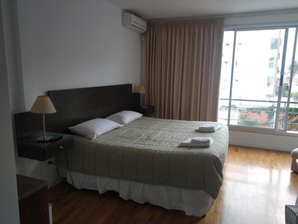 une chambre avec un grand lit et une grande fenêtre dans l'établissement caseros apart, à Salta