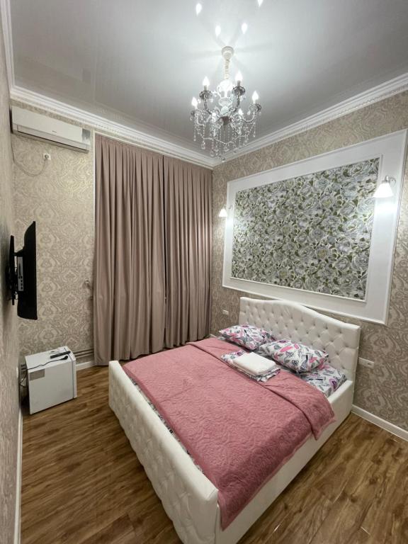 a bedroom with a bed and a chandelier at Гостиница АСКАР in Shymkent