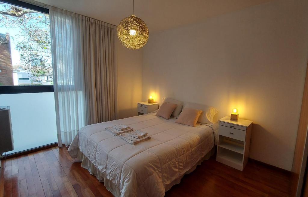 1 dormitorio con 1 cama con 2 mesitas de noche y 2 luces en Cálido y hermoso Dpto. en excelente zona de Rosario en Rosario