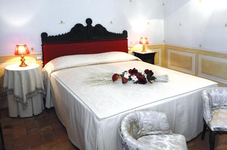a bedroom with a bed with flowers and two chairs at Antica Sosta in San Quirico dʼOrcia