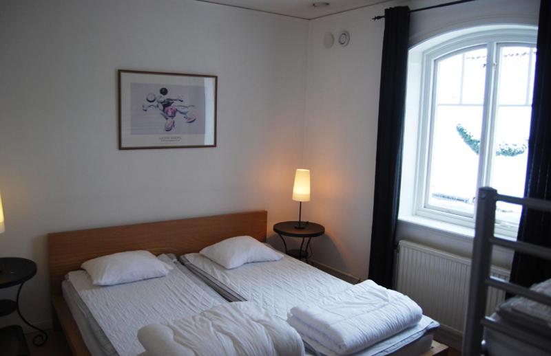 Bett in einem Zimmer mit einem Fenster und einem Bett sidx sidx sidx sidx in der Unterkunft Wisby Jernväg Hostel in Visby