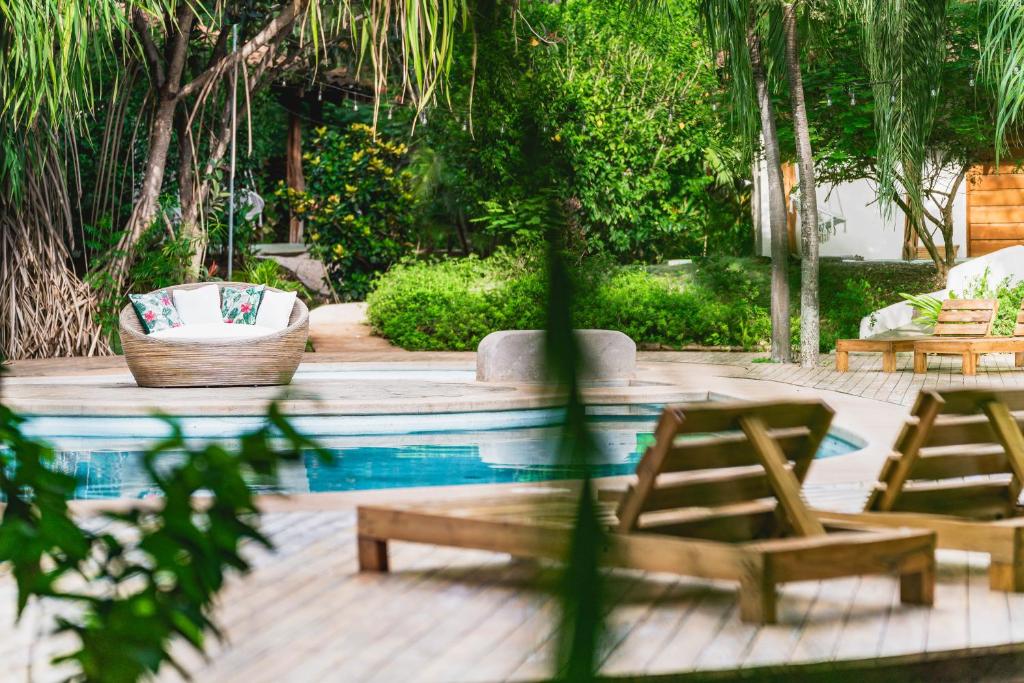 una piscina con 2 sillas y un par de mesas en SoulShine en Playa Avellana