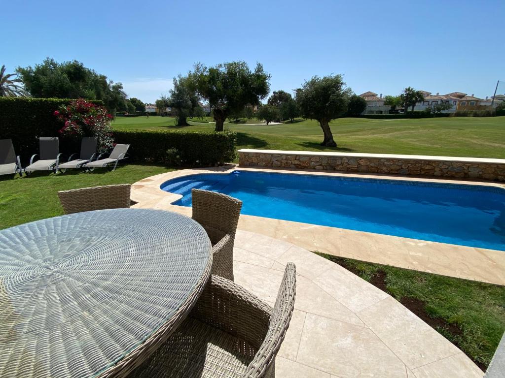 a table and chairs next to a swimming pool at Mar Menor Golf Villa - Frontline Detached - Heated Pool in Torre-Pacheco