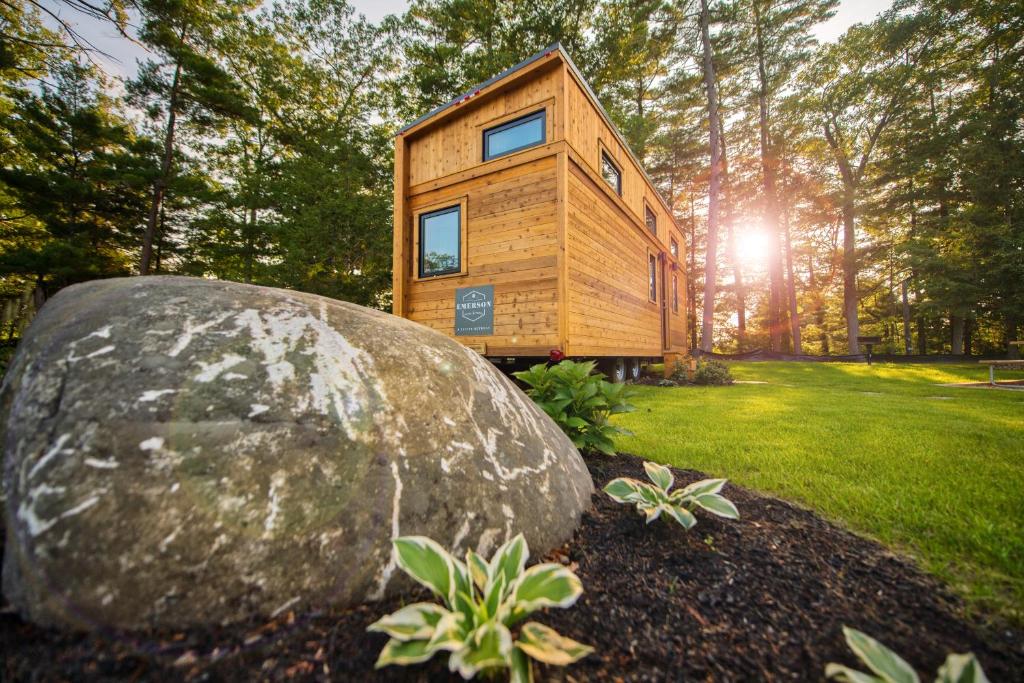 a wooden house in a field with a rock at Tuxbury Pond Camping Resort Tiny House Emerson in South Hampton