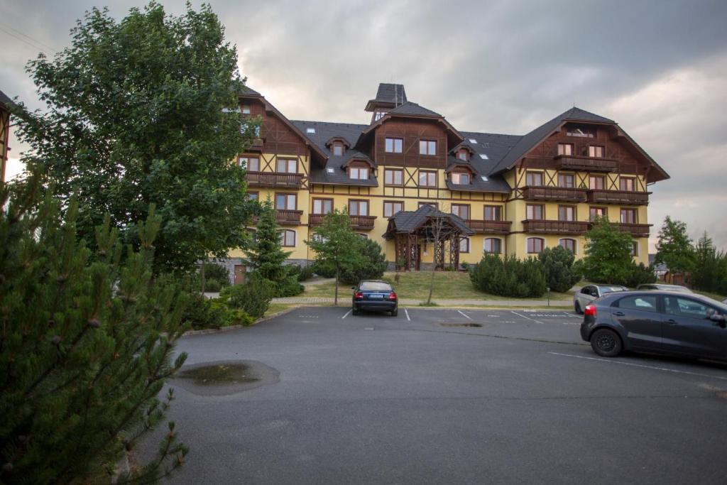 a large building with cars parked in a parking lot at Apartmán Angel in Veľká Lomnica