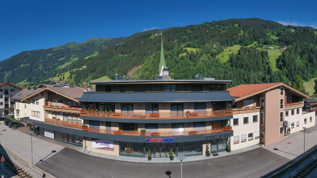a building in front of a mountain with a church at Sport Apart in Zell am Ziller