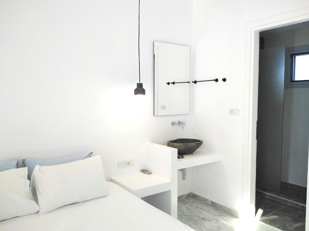 a white bedroom with a bed and a sink at Nissos Ios in Mylopotas