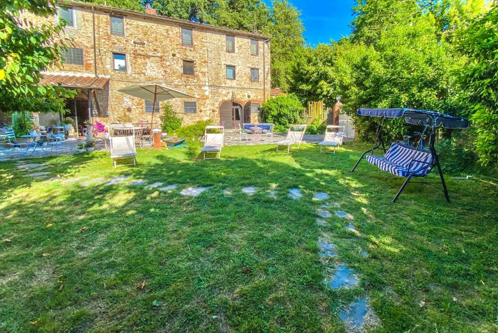 - un groupe de chaises dans une cour avec un bâtiment dans l'établissement Guest House Antico Frantoio Pietrasanta Affittacamere, à Pietrasanta