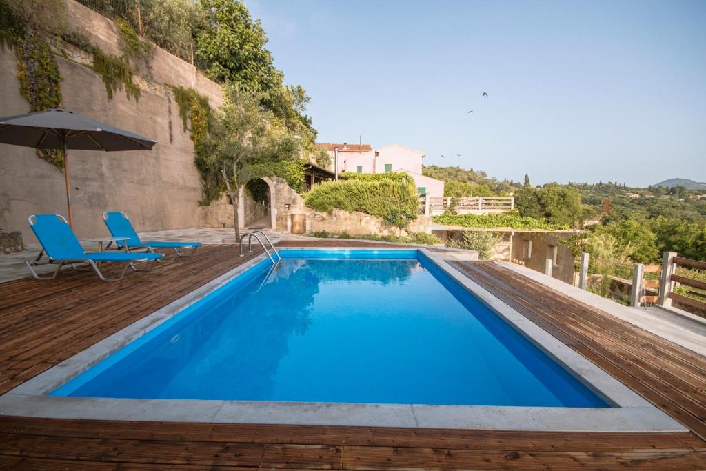 a large blue swimming pool with blue chairs and an umbrella at Corfu Tramezzo designer's House in Bastoúnion