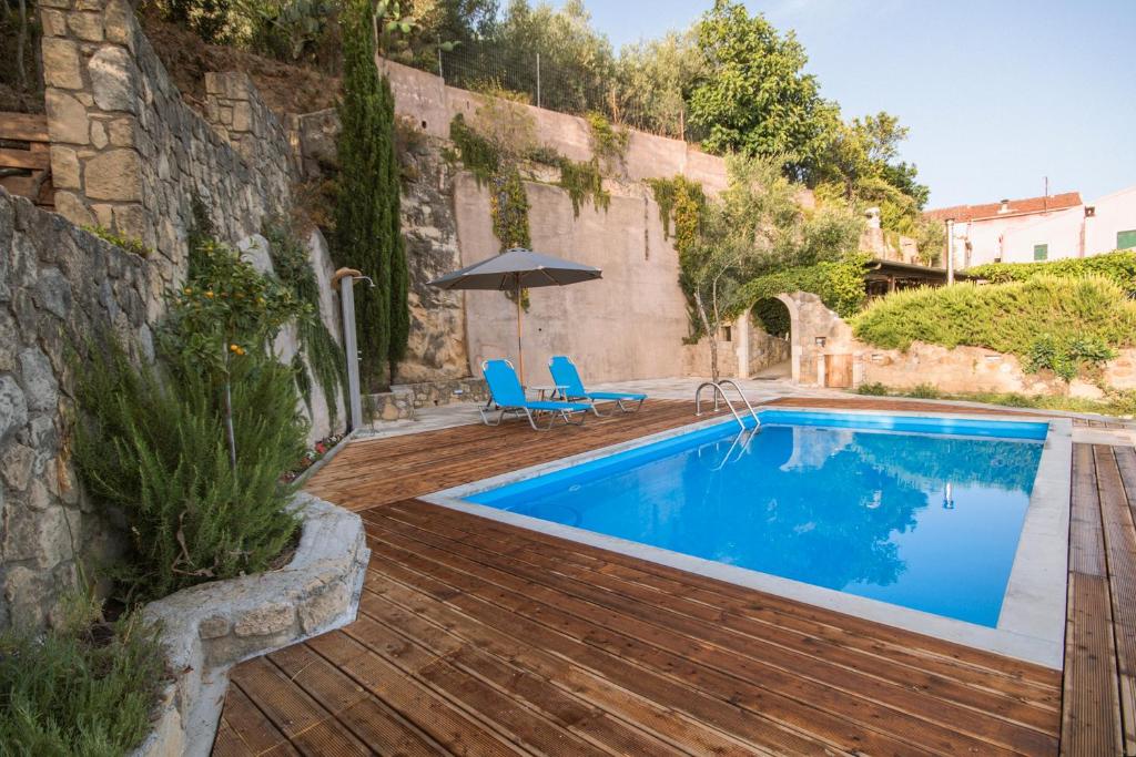 a swimming pool with a wooden deck and an umbrella at Corfu Tramezzo designer's House in Bastoúnion