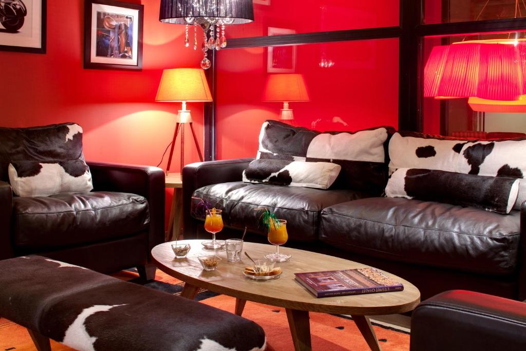 a living room with black leather furniture and red walls at Chalet-Hôtel La Marmotte, La Tapiaz & SPA, The Originals Relais in Les Gets