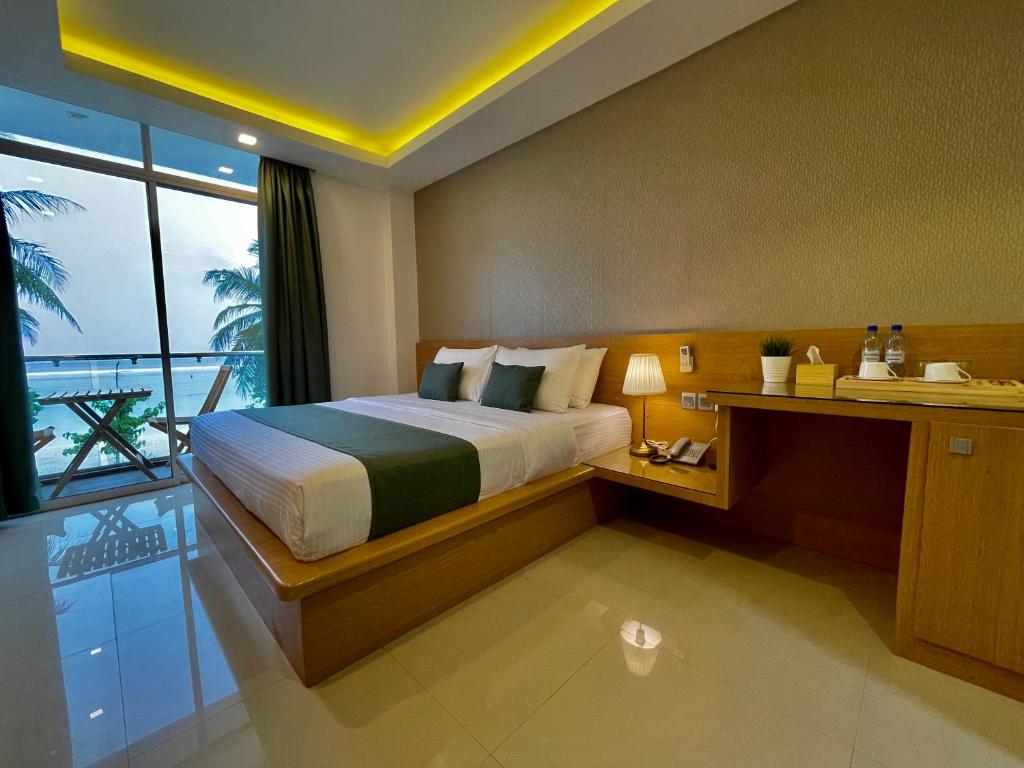 Huvan Beach Hotel at Hulhumale في هولهومالي: غرفة نوم بسرير ونافذة كبيرة